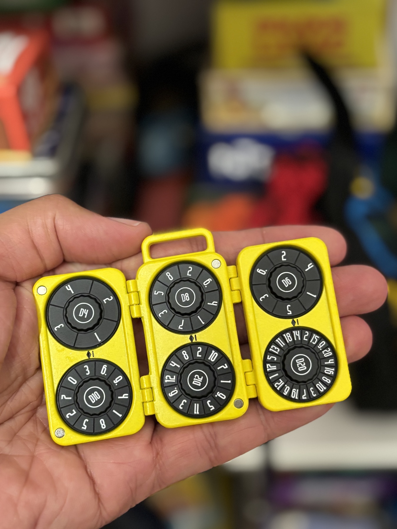 An open yellow Cardyhedron Fold mechanical polyhedral die held in one hand