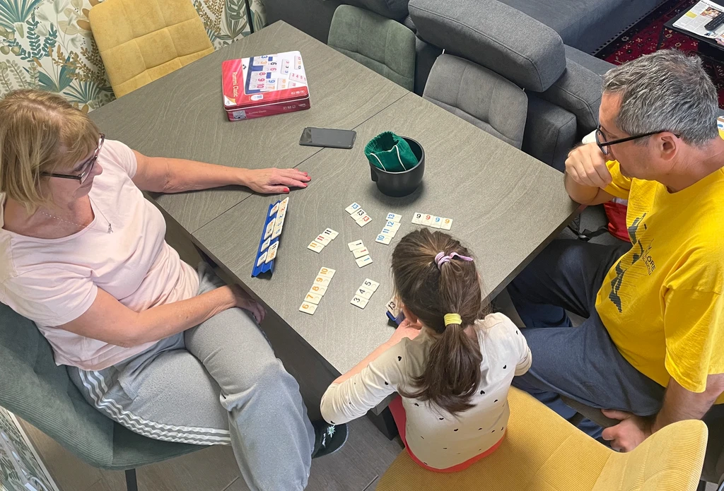 Rummikub game being played by grandparents and grandchild on Saturday afternoon